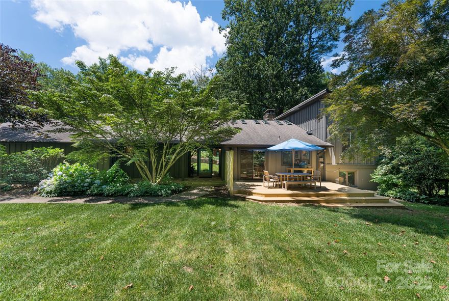 Tucked away on 2.5 peaceful acres in the heart of South Asheville, this spacious four-bedroom custom-built residence offers a rare combination of seclusion and convenience in the Asheville market. Surrounded by mature trees and beautifully landscaped gardens, the property features expansive outdoor living with more than an acre of fenced yard and multiple decks for quiet mornings or lively gatherings. The airy, open split-level floor plan is enhanced by vaulted ceilings and skylights that bathe the interior with natural light. The large gourmet-style kitchen flows seamlessly to outdoor spaces and includes generous work surfaces and a built-in desk area. The main-level primary suite, fully renovated in 2020, features a custom closet and dressing room. Downstairs, a cozy den with fireplace and wet bar creates an inviting second living area, while the lower level offers a guest suite and multiple flex spaces. Located within the Deerhaven enclave with no city taxes, this property feels worlds away while still being close to top rated schools, Biltmore Park, Asheville shopping, dining and walking trails. Whether you are looking for a private retreat or a home designed for entertaining, this unique Asheville property delivers space, style and unmatched access in one of the region’s most sought-after areas.