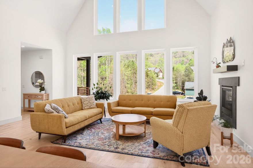 For the buyer stepping into a new chapter and unwilling to compromise on space, design, or location, this 2023-built residence offers a rare blend of modern comfort and elevated living near Reems Creek Golf Club.
The main living area makes an immediate statement with a soaring 25-foot ceiling, oversized windows, and an open-concept layout that feels both expansive and welcoming. At the center of the home, the kitchen is built to anchor daily life and effortless entertaining, featuring a large island, custom cabinetry, and upscale finishes throughout. The main-level primary suite offers a private retreat with a spacious walk-in closet and a beautifully appointed bath, while additional bedrooms and flexible living areas provide room for guests, work, recreation, or multigenerational living. Built with today’s lifestyle in mind, the home also includes EV charging outlets and Energy Star efficiency, pairing modern convenience with long-term value. Set in a private gated community setting with easy access to Weaverville’s local charm and downtown Asheville’s dining and culture, this is a rare opportunity to own a newer home that supports both the way you live now and where you are headed next.