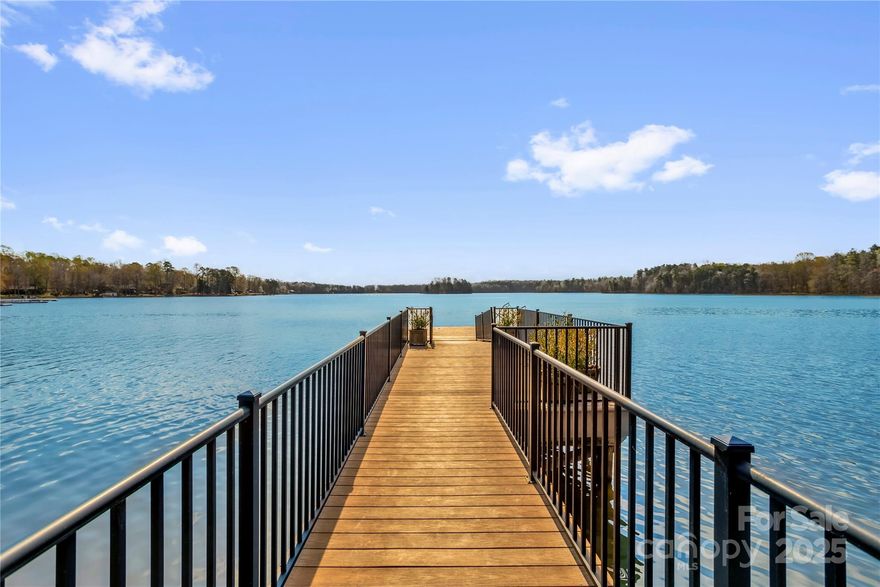 Lakefront Living at Its Finest! Stunning waterfront home with breathtaking views, deep water access, private pier in a quiet, no-HOA neighborhood minutes from I-85 and Salisbury. Fenced, irrigated yard features boat ramp, hot tub, & expansive outdoor spaces, including large deck & covered patio. The chef’s kitchen boasts exotic granite, KitchenAid 6-burner gas cooktop, double convection ovens, Electrolux double fridge/freezer, beverage fridge, & custom cabinetry. Main level includes two bedrooms, full bath, & half bath. Upstairs, primary suite features a wall of windows to the lake, spa-like bath, & massive walk-in closet. Finished walkout basement offers a spacious entertainment room with fridge, microwave, & fireplace, plus double sink full bath, flex room, exercise room, & storage space. The FROG is currently used as office. Newer front & garage doors, gracious covered front porch, & two built-in safes add to the appeal. A rare opportunity for luxury lakefront living—don’t miss it!