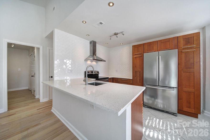 MOVE-IN READY! This stylishly updated townhome features a stunning kitchen with quartz counters, counter-to-ceiling herringbone tile, chimney vent hood, and new cabinetry with smart storage. The open layout flows into a vaulted living room with views to the enlarged deck through brand-new energy-efficient sliding doors. A converted garage offers a flexible space featuring LED lighting and thick Berber carpet. Bathrooms feel spa-like with floating vanities, efficient toilets, designer lighting, and floor-to-ceiling shower tile with a seamless glass door. A convenient half bath offers direct access to one bedroom. Rich, mixed-width birch wood flooring runs throughout. Modern updates, thoughtful design, and versatile spaces make this home a rare find! Must See!