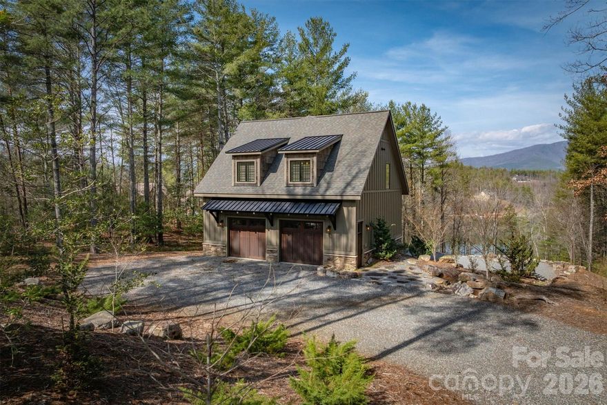 Perched on a stunning 2+ acre homesite within prestigious Old Wildlife Club, 1195 Old Wildlife Club Drive offers one of the most breathtaking vantage points on Lake James. This rare property captures expansive long-range water views paired with the Blue Ridge Mountains, a combination seldom found on Lake James and one that creates a truly unforgettable setting. An easy-to-access, year round boatslip just a short UTV ride away is included! The thoughtfully designed “Garagemahal” provides comfortable living today while leaving plenty of room to build a future dream home on the spacious parcel. The massive two-bay garage is ideal for lake living, with one extra-long bay designed to accommodate a boat, lake toys, or workshop space.Above the garage, the main living area features vaulted ceilings and a dramatic wall of windows that perfectly frame the sweeping lake and mountain views. The open living space flows easily into an ample kitchen with built-in features and granite countertops throughout, making full use of the space for everyday living or entertaining. The primary suite offers a peaceful retreat with a spacious bathroom and stand-alone soaking tub, while additional flexible living space on the garage level includes a full bathroom and room that could serve as a guest area, office, or recreation space. A washer and dryer, generous storage, low-maintenance Hardy siding, and a stone foundation add to the home's practicality and durability. Outdoor living truly shines here. A large Trex deck stretches across the home, showcasing the panoramic views, while a covered patio below and firepit area overlooking the sparkling waters of Lake James provide incredible spaces to relax and entertain. Ownership also includes access to Camp Lake James, offering a lakefront pool, fitness center, tennis and pickleball courts, dining, social events, and marina access. The owners are even willing to share their previous custom home design plans, making this an exceptional opportunity to enjoy the property now while planning your ultimate Lake James retreat.