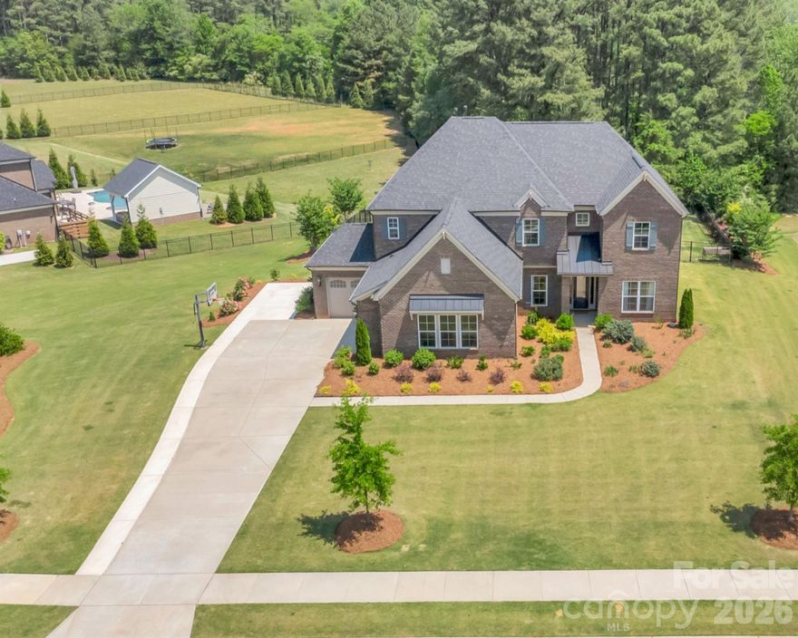 Welcome to a private retreat where luxury, space, and unforgettable outdoor living come together beautifully.
Set on nearly an acre and backing to serene woods, this stunning two-story brick home offers a rare sense of privacy while still being close to everything. From the moment you arrive, the setting alone feels special, but it’s what’s inside that truly sets this home apart. The heart of the home is a chef-inspired kitchen designed to impress, featuring quartz countertops, a designer tile backsplash, gas cooktop, custom cabinetry, and a massive oversized island that anchors the space and invites gathering. A butler’s pantry and walk-in pantry add both beauty and function, while the open layout flows effortlessly into the main living areas. Just beyond, the two-story great room showcases a striking brick fireplace and coffered ceilings, creating a dramatic yet inviting space filled with natural light, perfect for both quiet evenings and entertaining on a larger scale. The main-level primary suite offers a true retreat, complete with a generous layout and a spa-like bath featuring a freestanding soaking tub, large walk-in shower, and expansive walk-in closet—designed for both comfort and everyday luxury. Step outside and experience what truly makes this home unforgettable. The backyard has been transformed into a private oasis, featuring a gorgeous custom pool and spa, expansive decking, and a wooded backdrop that provides exceptional privacy. The covered porch seamlessly connects indoor and outdoor living, offering the perfect space to relax, host, and enjoy the setting year-round. Upstairs, the home continues to impress with a spacious loft, dedicated media/bonus room, and three additional bedrooms with two full baths, providing flexibility for guests, work-from-home needs, or everyday living. A 3-car garage, generous laundry room, and thoughtfully designed spaces throughout add both convenience and function. Located in the highly sought-after Weddington High School district and just minutes from shopping, dining, and Providence Road, this home offers the perfect balance of luxury, privacy, and location.
 If you’ve been searching for a home that feels like a true retreat, this is one you won’t want to miss.
