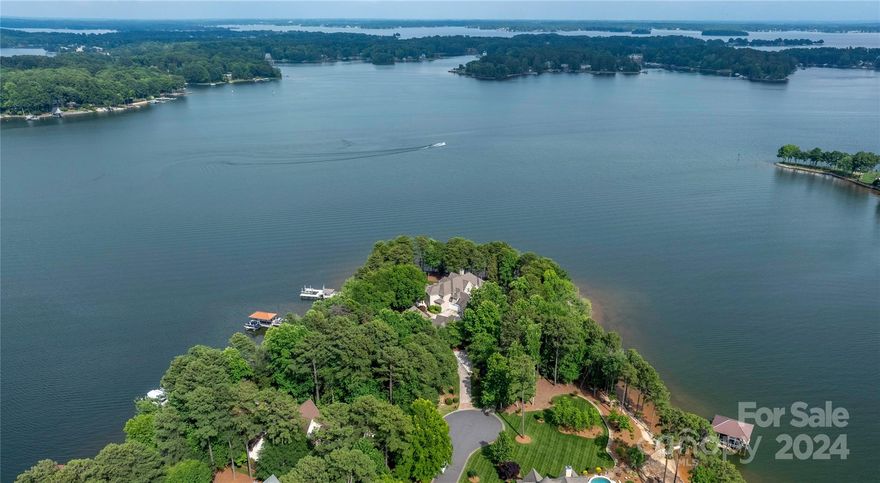 Welcome to this magnificent Lake Norman waterfront home boasting 6037 sq ft of luxurious living space. Situated on a sprawling 1.36-acre point lot with 360-degree views, this 5-bedroom/4.5-bath residence offers unparalleled privacy & serenity. Step inside to find a grand foyer leading into the spacious living areas, featuring soaring ceilings, hardwood floors, and panoramic windows that flood the home w/ natural light. The gourmet kitchen is a chef's dream, with high-end appliances, custom cabinetry, & a large island for entertaining. The primary suite is a true retreat, with a spa-like ensuite bath overlooking the lake. Each additional bedroom is generously sized with views from every window. The separate living quarters are perfect for guests or extended family. Outside, the expansive patio & terrace are the perfect spot to take in the breathtaking views. The backyard offers endless possibilities for outdoor entertaining & recreation.
