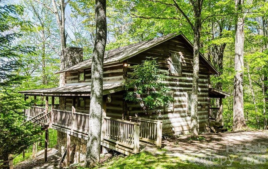 Rare find in Wolf Laurel!  Beautiful 4 bedroom, 2 bath log cabin on double lots with only one assessment, just minutes from popular Hatley Pointe Ski Resort soon to feature mountain biking trails. Tucked away in a peaceful and private setting, surrounded by mature trees and wildlife, this fantastic mountain home radiates warm and cozy comfort with rich wood finishes, rustic touches and exposed beams that create a welcoming, relaxed atmosphere. Warm and inviting great room anchored by floor to ceiling gorgeous stone fireplace for chilly nights. Functional galley kitchen with handcrafted cabinetry. Two bedrooms and a full bath finish out the main floor along with an oversized pantry. Two additional bedrooms and a full bath plus an open office space or sitting area await upstairs. A full, unfinished basement offers endless possibilities. Wrap around, covered porches invite you to enjoy the outdoors, rain or shine. Affordable and move-in ready, this home is a prime short-term rental opportunity—schedule your visit today!