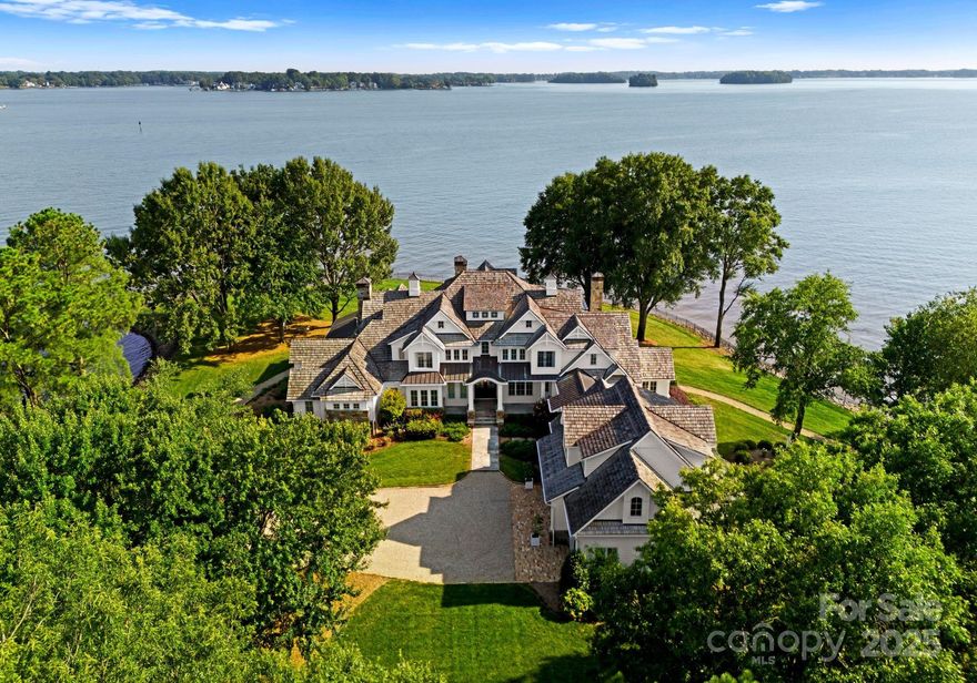 Experience the pinnacle of luxury, Breakwater, a New England-inspired estate, perfectly positioned on a private 1.71-acre peninsula boasting 1,100 feet of shoreline & 180° panoramic water views from sunrise to sunset. The lush grounds feature mature trees, a luxurious southern-facing pool & spa, & meticulously manicured landscaping. A rare No Profile boat lift with a covered dock enhances the waterfront experience. The property is securely fenced, access through an electric gate, ensuring privacy & exclusivity. Inside, the estate exudes refined elegance with extensive custom millwork, cathedral ceilings, & expansive windows framing endless lake views. The gourmet kitchen boasts a large island, scullery, & fold-away doors that blend indoor-outdoor living. The home includes a theater room, bar atelier, & a stunning enclosed breezeway leading to the carriage suite. Signature features include a Control 4 smart home system, retractable screened porch with a fireplace, & outdoor kitchen.