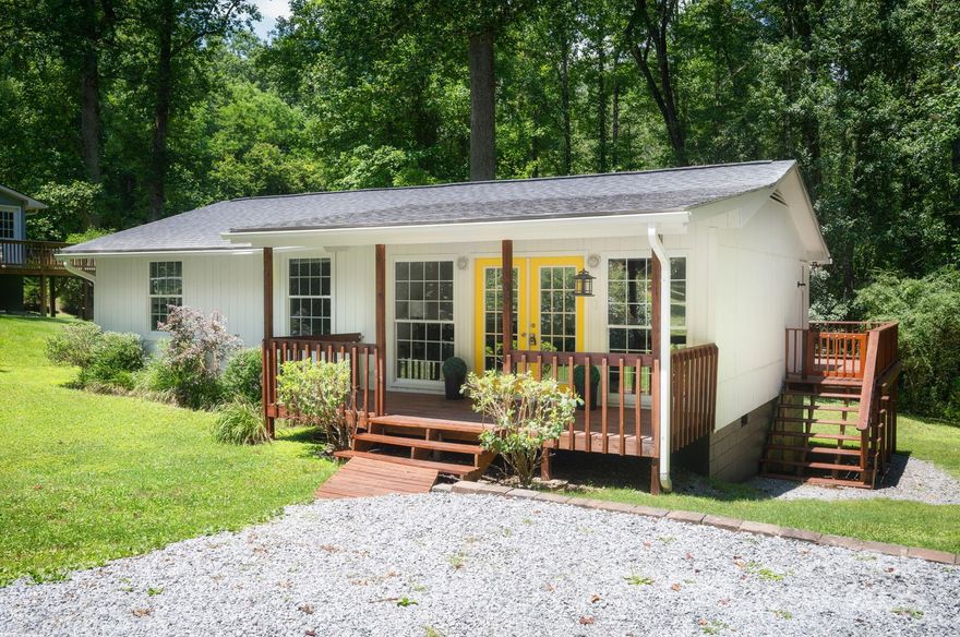 Nestled off a quiet, wooded lane only 1.2 miles from downtown Brevard, this charming mountain cottage blends privacy with convenience. The inviting covered front porch welcomes you into the spacious living room with floor to ceiling windows. The oversized eat-in kitchen with abundant cabinetry is perfect for a home cooked meal. The home offers three bedrooms—including a newly updated tile surround in the hall bathroom. Freshly painted interior, exterior, and stained decks and porches. New roof in 2019 and new heat pump installed in 2023. The large rear deck overlooks a lush yard bordered by trees and a creek. Just around the corner from the Brevard Music Center and downtown Brevard. Minutes to Pisgah National Forest and countless trails, this property delivers both comfort and mountain lifestyle.