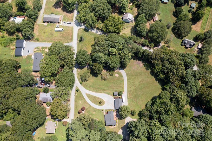 7.36 acres, 921 feet road frontage on Alton St. 412 feet frontage on Midas Spring Road. Land can be subdivided. Beautiful property with cleared acreage and mature hardwood forest. 33x22 carport , 24x30 shop heated with wood stove. Has 220 and water in shop. 24x12 carport attached to shop. 28x25 patio with pergola and large deck overlooks rear yard. Covered front porch. Home total renovation in 2002. Office space could be used as 3rd bedroom. New roof, gutters 2021. New well pump and tank 2022. New HVAC system 2025. House set up to connect to a generator. City water and sewer available. Land classified as unincorporated, no city tax. Interesting history fact, see pictures of the fountain of youth on property built in the late 1800s. 20 minutes to Charlotte, Airport and Lake Norman. Convenient to Mountain Island Lake and Latta Park.