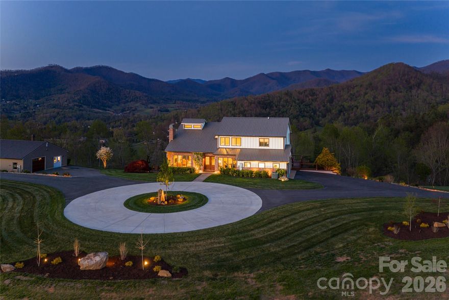 Welcome to 83 Cozy Mountain Lane, set on approximately nine private, gated acres in the Blue Ridge Mountains and offering a rare blend of refined mountain living, expansive scale and exceptional 360-degree views. Ideally just minutes from downtown Weaverville and approximately 15 minutes to Asheville, the property provides convenient access to dining, arts and culture while remaining close to outdoor destinations including the Blue Ridge Parkway and Pisgah National Forest. Spanning approximately 4,963 square feet, this four-bedroom, four-bath residence is thoughtfully positioned to capture sweeping long-range mountain views from the moment you enter the driveway and carry through nearly every room.  A striking great room with a stone gas fireplace sets the tone upon entry, seamlessly flowing into a light-filled living area framed by expansive picture windows that capture sweeping mountain views. From here, go out onto the Trex deck with a gas fire pit, overlooking a resort-style in-ground pool, patio and custom stone fire pit, an ideal setting for elevated, year-round entertaining. The kitchen serves as the heart of the home, featuring a suite of KitchenAid appliances, including a wall oven, microwave, five-burner gas cooktop and refrigerator, complemented by a Bosch dishwasher. Leathered granite countertops, a large island, stainless apron-front sink and under-cabinet lighting balance function with understated luxury. A dedicated office, integrated speakers and a well-appointed mudroom and laundry suite complete a main level that’s as functional as it is refined. Upstairs, the primary suite offers a private retreat with vaulted ceilings, transom windows and a Juliet balcony overlooking the pool and surrounding mountains. The spa-inspired bathroom features a freestanding soaking tub set before a picture window, dual marble vanities, a spacious walk-in shower with pebble stone flooring and refined stone accents. Two additional guest bedrooms, full bath and a loft living area complete the upper level. The lower level expands the home’s versatility with full secondary living quarters, including a recreation room, living room with wood-burning stove, complete kitchen with stainless appliances, dining area, guest bedroom and full bath. Dedicated systems, including dual water heaters and mini-split climate control, make this space ideal for guests, multigenerational living or extended stays. A detached, fully climate-controlled outbuilding/garage adds further flexibility. In addition to generous garage space, the structure includes a dedicated office, ideal for remote work, fitness or creative use, complementing the property’s overall sense of scale and privacy. Beyond the home, the property unfolds into a private, gated mountain estate defined by rare, gently sloping ridge-top land. The approximately nine acres are usable and visually striking, offering open areas suited for recreation, gardens or expanded outdoor living, all framed by panoramic long-range views. Offering a rare combination of acreage, privacy, proximity and commanding mountain views, 83 Cozy Mountain Lane is designed for everyday living and exceptional entertaining.