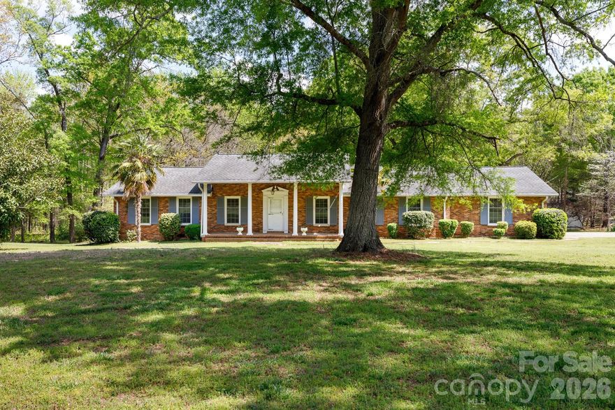 This classic brick ranch sits on nearly 2.5 acres of level, sprawling land, offering the kind of space and privacy that is becoming harder to find. Imagine starting your mornings on the front porch or hosting summer cookouts on the screened-in back porch, which features a unique built-in brick fireplace grill. The massive yard provides plenty of room for hobbies or projects, supported by two large storage buildings and a side-load two-car garage. Inside, the home is designed for comfortable living with a spacious kitchen featuring double wall ovens, a refrigerator that stays, and ample cabinet storage. The living room serves as a cozy centerpiece with its floor-to-ceiling brick fireplace and custom built-ins, while the large laundry room adds extra utility with a dedicated sink and a cedar closet. With a brand-new HVAC system installed just a year ago, the heavy lifting is done, allowing you to move in and enjoy this quiet retreat while adding your own personal style over time. Beyond the property line, you are just a short drive from the lake, along with popular local shopping and dining destinations, giving you the best of a secluded homestead with modern conveniences just around the corner.
