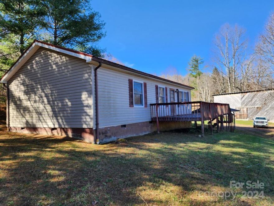 This small but well-arranged modular home is located in the Bowditch/South Toe area just off of NC 80S. The 1.73-acre lot is well manicured and has good mountain views. If you need extra storage, there is a dry full basement and a large barn. There is an attractive carport that's perfect for keeping the frost off of your car. The home has two full bathrooms and two large bedrooms including the primary. The other bedroom is smaller but would make a great office. The roof is metal and will last a lifetime. This home is part of an estate and is being sold "As Is". The interior would benefit from paint and the deck needs some boards replaced. This home could be ready to move in with only a few days of work. The property received no real damage from Helene and is not near any flood plain. This modular is located only 8 miles from beautiful downtown Burnsville. Hiking trails, Mt Mitchell and the Blue Ridge Parkway are just minutes away. Come and check out this great little home and property.