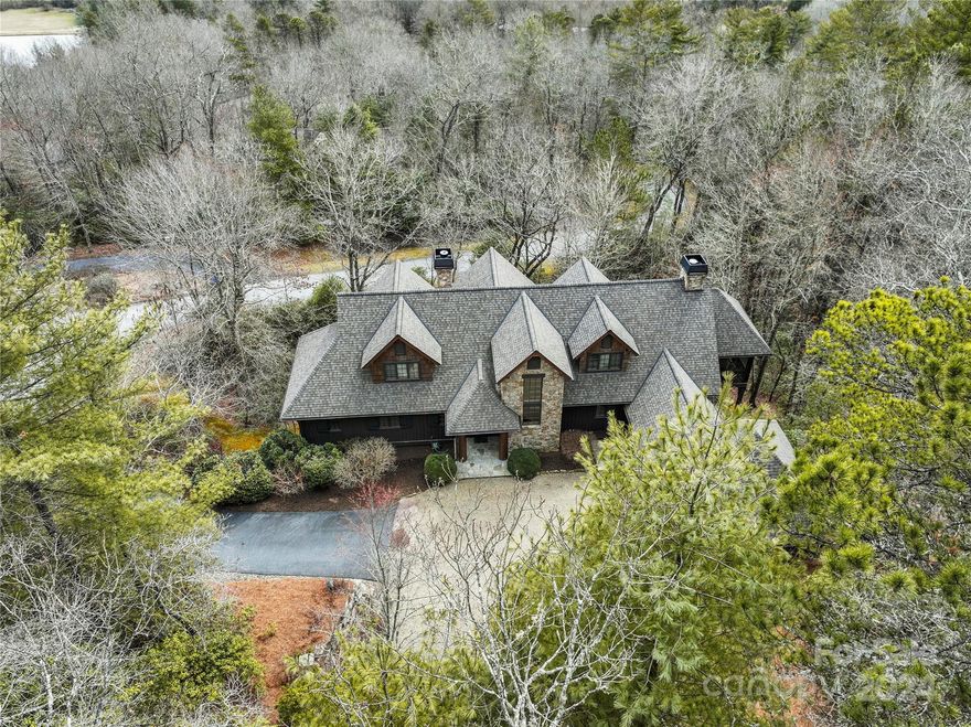 This stunning PLATT designed home is located close to both downtown Brevard and Pisgah National Forest in the highly desirable Straus Park community, a beautiful and peaceful neighborhood offering tennis, a pool, and a community lake. Situated at the end of a quiet cul-de-sac in a private and natural setting, this home is constructed of authentic materials to match the setting. The stone, wood, and bark exterior is paired with antique heart pine floors and beams, laurel and locust handrails, and tongue and groove wood ceilings on the interior.  Large windows connect the interior to the outdoors and provide ample natural light throughout the home, and the screened porch, complete with rock-faced wood burning fireplace, is surrounded by trees, providing a haven for relaxing and entertaining. While the main level of this Energy Star Certified home offers the convenience of a two car garage and the primary bedroom suite, a wood paneled elevator assures easy access to the lower level.