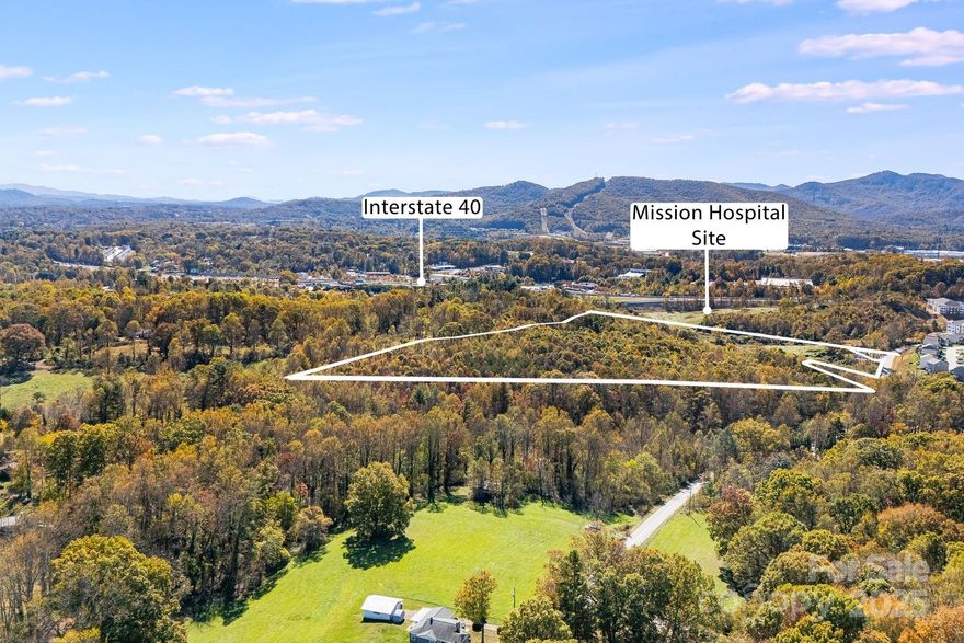 This gorgeous raw land has excellent development potential.  Comprising 21 acres more or less (see attached survey) and sharing a boundary line with the new Mission Hospital site in West Asheville just off Patton Ave.  Featuring long range mountain views and a lovely creek running through it. Suitable for multifamily buildings. 12 units per acre.
Additional 12 acres available from neighboring owners MLS# 4313794 (see photos).
A portion of the property is in a floodplain.