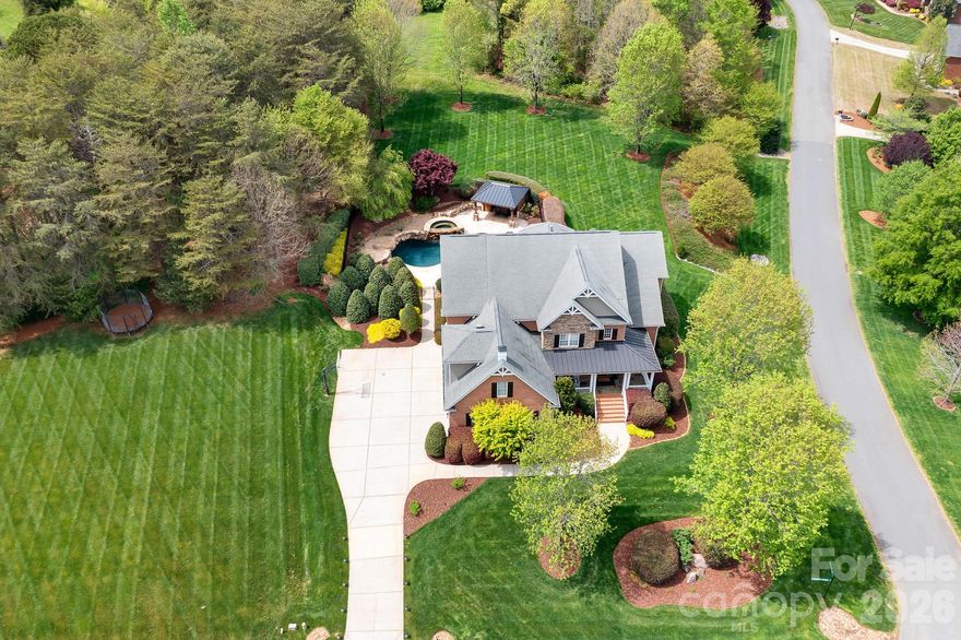 This is the kind of home people wait for in Davidson-where refined design, exceptional functionality & a true resort style outdoor experience come together in one of the area's most coveted zip codes around Lake Norman. From the moment you arrive, the home feels both impressive and comfortable. The expansive wraparound porch, complete w/ a charming hanging swing, greets you and as you enter the home, gleaming real hardwoods guide you into a stunning two-story foyer that offers a captivating view of the open living space. The pretty dining room sits to the left and has beautiful moldings and brand new lighting. It flows seamlessly into the kitchen which offers timeless wood cabinetry, a GAS COOKTOP, a brand new wall oven and microwave, and a hidden beverage fridge. Just off the kitchen, the breakfast area is lined with floor to ceiling windows that showcase the views of your backyard oasis. From here, you step out onto the spacious travertine deck-perfect for entertaining or outdoor dining. The living room is a standout with tons of natural light and a dramatic floor-to-ceiling stone fireplace that really anchors the room with a clean, timeless look. The main level also features a home office with a built-in desk/cabinetry, a BEDROOM & FULL BATH on the main, plus an ADDITIONAL MAIN LEVEL FLEX SPACE that provides versatility for any lifestyle. A well appointed drop zone & tons of storage throughout. Upstairs, double doors lead you to a serene primary retreat w/ ensuite bath that offers an enormous walk-in shower w/ dual shower heads, dual vanities, a soaking tub & a huge closet w/ built ins. Two additional spacious bedrooms + a huge bonus room, the laundry room and a WALK-IN ATTIC STORAGE room complete the space upstairs-all with BRAND NEW CARPET. What really sets this home apart is the backyard-a true outdoor oasis that you rarely see done this well. The deep saltwater pool features a cascading waterfall spa, a tanning ledge with included loungers, and a jumping rock. It's surrounded by travertine decking, mature, professional landscaping designed specifically for privacy, and a PAVILION w/ a POOL BATH, bar/tv area & mini fridge-making it incredibly easy to host without ever needing to run inside. Every detail has been carefully considered to deliver both luxury and livability. This FULL BRICK HOME sitting on NEARLY 1 ACRE is just 10 minutes to Downtown Davidson so you get the benefits of living in Davidson with low Iredell Co taxes. You'll love living here!