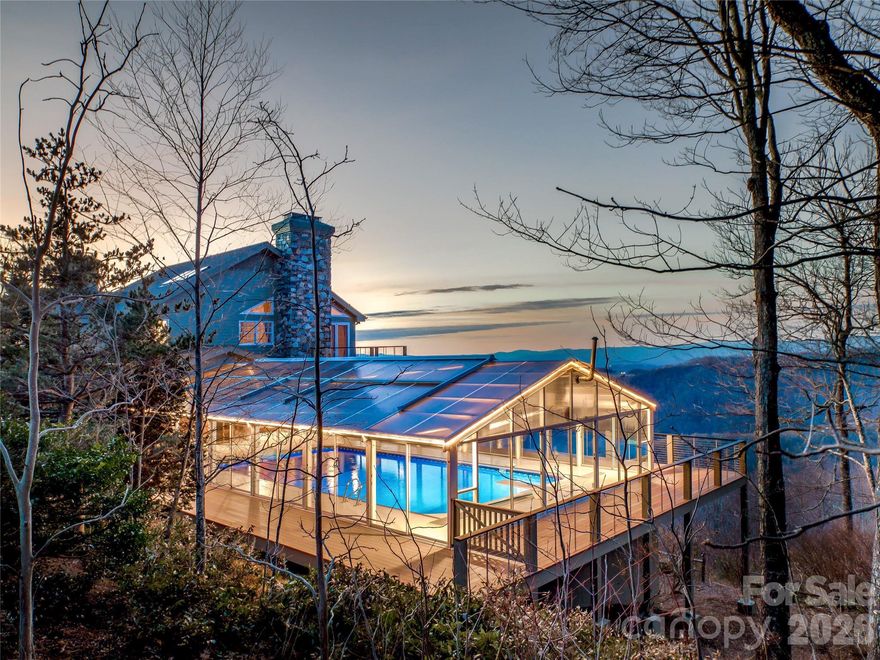Commanding one of Asheville’s most awe-inspiring mountain panoramas, this extraordinary private estate offers over 7,000 square feet of dramatic architecture, refined craftsmanship, and beautifully curated interiors—set on approximately 5 acres that blend thoughtfully landscaped spaces with peaceful, natural woodland. Recently refreshed and meticulously maintained, it delivers a rare combination of sophistication, comfort, and enduring quality.
Walls of glass frame sweeping, layered Blue Ridge vistas, while expansive wraparound decks invite connection, celebration, and quiet reflection in every season. A resort-style pool and spa, hot tub, and sauna create an outdoor sanctuary designed for both everyday relaxation and unforgettable entertaining. Inside, the chef’s kitchen anchors the home with beauty and function, complemented by a wine room, billiards room, and generous gathering spaces ideal for both intimate evenings and grand occasions.
The entire second-floor primary suite feels like a private retreat, complete with a fireplace, exercise room, wet bar, laundry room, private decks, and a richly appointed study—an indulgent escape with exceptional privacy. An elevator, a whole-house generator, adds ease, security, and everyday practicality.
Three-car garage on the main level and a one-car garage in the basement with workshop/storage is a bonus.
Perfectly positioned just minutes from downtown Asheville’s renowned dining, galleries, theater, boutique shopping, and the iconic Grove Park Inn—and moments from the scenic beauty and adventure of the Blue Ridge Parkway—this is more than a residence. It is a lifestyle, an experience, and a rare opportunity to live at the pinnacle of Asheville’s mountain living.