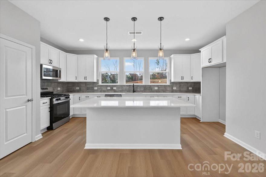 This 3-bedroom townhome offers a first-floor guest suite and 2-car garage. The main level features a private terrace, 9'ceilings, and an open living space. The kitchen includes a large island, quartz countertops, tile backsplash, 42”cabinets, double trash pull-out, stainless steel sink, gas range, and dishwasher.  Upstairs, the primary suite has a walk-in closet and tiled shower, along with an additional guest suite and full bath.