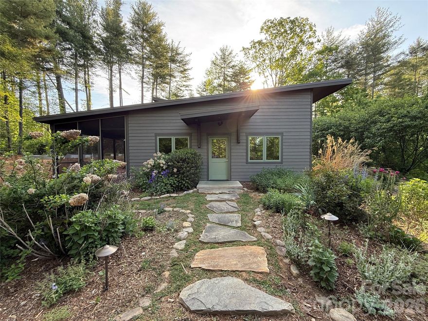 Tucked into the trees yet just minutes from the heart of vibrant South Asheville, this contemporary passive/PV solar home offers the rare combination of privacy, sustainability, and convenience. Built in 2016 and never before offered to market, this thoughtfully designed home sits on an expansive 2.76-acre lot that feels like your own private forest sanctuary. Inside, you’ll find clean modern lines, abundant natural light, and a warm, welcoming atmosphere. Large windows frame serene forest views, creating a seamless connection between indoors and out. A cozy loft provides flexible space inside while the large screened porch creates the perfect place to enjoy the outdoors from the comfort of your home. Custom finishes throughout including, maple doors and trim, handmade steel ladder to loft, and many more show just how much care went into the custruction of this unique home. The property is a true gardener’s dream, featuring established fruit trees, a flourishing herb garden, and berry patch. With solar already in place, you’ll enjoy energy efficiency and sustainable living from day one. Conveniently located close to shopping, dining, and amenities of South Asheville, yet surrounded by the sights and sounds of nature, this is a rare opportunity to own a contemporary home that feels worlds away—while keeping everything you need within easy reach.