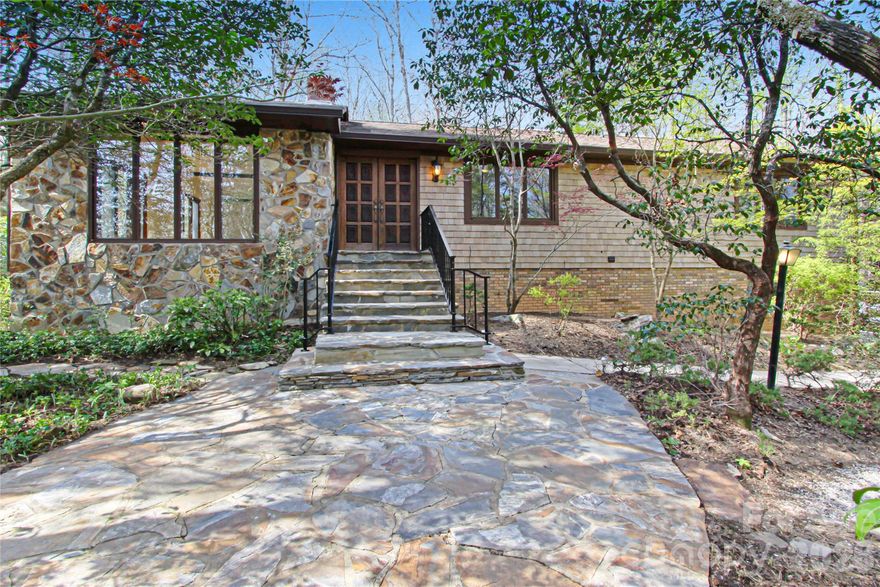 Privately positioned at the end of a cul-de-sac in one of Brevard’s most naturally beautiful settings, this mid-century modern residence offers a sophisticated blend of architectural design, serene surroundings, and elevated mountain living. Originally built in 1977, the home has been thoughtfully preserved to showcase its clean lines, expansive glass, and seamless connection to the outdoors.

Dramatic floor-to-ceiling windows define the main living spaces, filling the home with natural light and framing the surrounding forest landscape. The open-concept living and dining area is anchored by an impressive statement fireplace, creating a refined yet inviting atmosphere for both everyday living and entertaining. Just beyond, a richly wood-paneled sunroom provides a warm, retreat-like setting that captures the essence of mountain living with a distinctly elevated feel.

The main level also features a private office, offering a quiet and functional space for work or study. On the lower level, a spacious family room with a second fireplace extends the living experience, while a generously sized bonus/bedroom with full bath creates an ideal guest suite or bunk room. With its layout and scale, the lower level presents an exceptional opportunity to create a fully independent living quarters.

Additional features include a two-car garage, a second laundry/workshop as well as a dedicated workshop space, ideal for crafts, storage, or creative pursuits. The setting offers a rare sense of privacy while remaining just minutes from the charm of downtown Brevard, as well as nearby parks, national forests, a racquet club, and a country club—providing access to an active, wellness-oriented lifestyle.

A distinctive offering that combines timeless design, flexible living, and an exceptional natural backdrop, this residence is well suited as a primary home or refined mountain retreat...