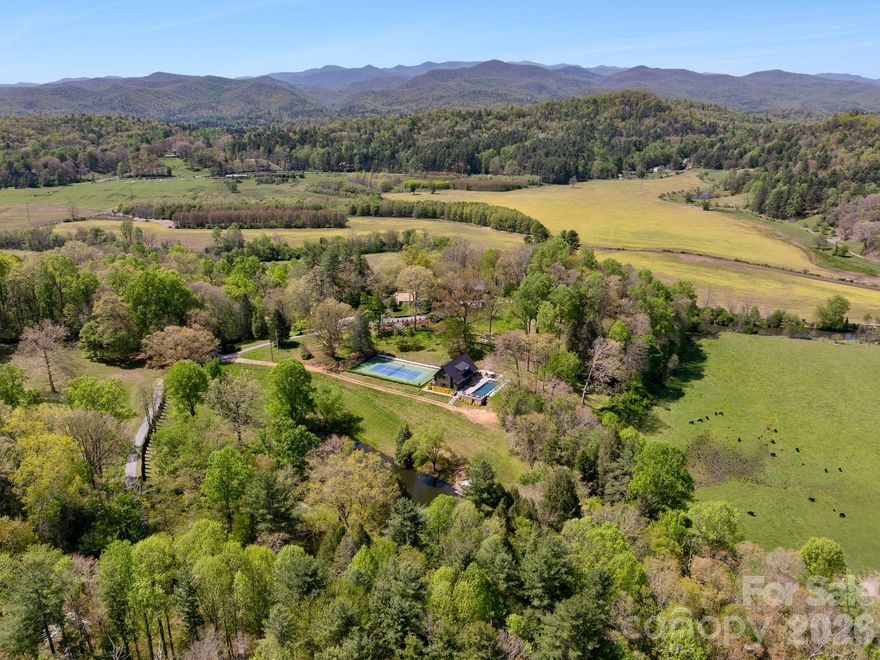 Blue Fish Farm is one of the most significant legacy offerings in the Blue Ridge Mountains, an extraordinary 160-plus-acre riverfront estate in Brevard, where privacy, scale and natural beauty converge along more than a mile of the French Broad River. Just minutes from Pisgah National Forest, DuPont State Forest and the region’s iconic waterfalls, this is a rare opportunity to own an irreplaceable Western North Carolina retreat. Originally designed by Platt Architects, the estate reflects a timeless mountain-modern aesthetic, blending refined craftsmanship with materials that echo the surrounding landscape. Across more than 12,700 square feet of combined living space, the property unfolds as a curated collection of residences, including a primary home, two guest cottages and a pool house, each thoughtfully positioned to capture river, pasture and mountain views. The main residence is warm, sophisticated and deeply connected to its setting, featuring heart pine flooring, natural bluestone, custom millwork and expansive windows that frame the landscape in every direction. Open-concept living spaces transition seamlessly to covered porches and outdoor entertaining areas, creating an effortless indoor-outdoor lifestyle synonymous with luxury mountain living. A series of guest residences provides exceptional flexibility for multi-generational living, private retreats or luxury rental potential. The Treehouse offers an intimate escape tucked into mature forest canopy, while The Hideaway delivers generous scale and privacy. The Pool House elevates the experience further with a full kitchen, fitness area, home theater, and direct access to a heated pool and tennis court, designed for relaxation and recreation. The land itself is the defining feature, over 160 acres of rolling pasture, hardwood forest, and curated grounds with three spring-fed ponds, an established trail system and expansive river frontage ideal for fly fishing, kayaking, and exploration. Whether envisioned as a private family compound, equestrian estate, working farm or corporate retreat, the possibilities are as expansive as the property itself. Despite its remarkable seclusion, Blue Fish Farm is less than 10 minutes from downtown Brevard’s vibrant dining, breweries and boutique shopping, and within easy reach of Hendersonville, Asheville Regional Airport and Asheville’s renowned cultural scene. Lake Toxaway and its private club amenities are also nearby, offering an added layer of lifestyle appeal. Blue Fish Farm is more than a property, it is a generational estate, a French Broad River sanctuary and a rare convergence of luxury, land and legacy in one of North Carolina’s sought-after mountain destinations.