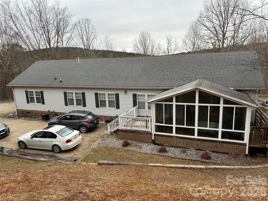 Opportunity awaits w/this large 4BR Doublewide on extremely private 2.53 acres w/frontage on Catheys Creek. Home is in livable condition but needs exterior work (huge deck is deteriorated, needs removal & is unsafe to walk on), so will not qualify for most types of financing & is priced accordingly (well below assessed value). Seller has an estimate for cost of deck removal. Enclosed front porch/sunroom has separate heat & air that hasn't been used regularly, so not counted in total square footage. Huge open great room w/living & dining areas. Kitchen w/breakfast bar, center island, and good cabinet & counter space. Primary Bedroom w/large walk-in closet and bathroom w/soaking tub & separate shower. There is a large concrete driveway w/lots of room for parking. Storage shed. There is also an outbuilding/studio. Call for details.
