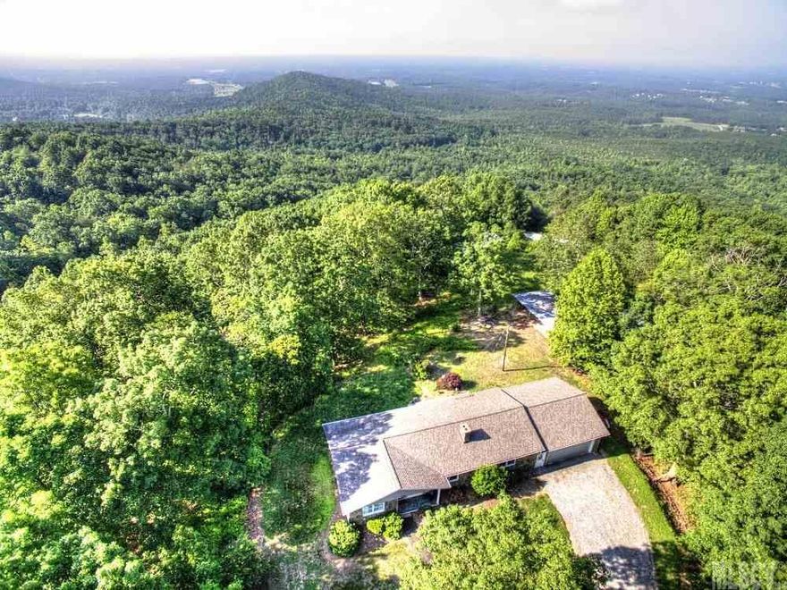 Nestled at the top of Barrett's Mountain, this exceptional NC Foothills residence offers a desirable single level floor-plan, 29 acres and multiple detached buildings.  This home provides a private setting yet is reasonably located near the amenities of Hickory and Taylorsville.  Interior features include a warm living room w/low maintenance laminate flooring, eat-in kitchen w/crisp cabinetry, stone back-splash and expansive built-in storage, spacious den w/stone fireplace w/stove insert, half bath and back patio access and two well appointed bedrooms each w/en-suite bathrooms.  An over-sized,attached two car garage provides additional storage or work space.  This home is truly in move-in condition and offers exceptional long range and natural views!