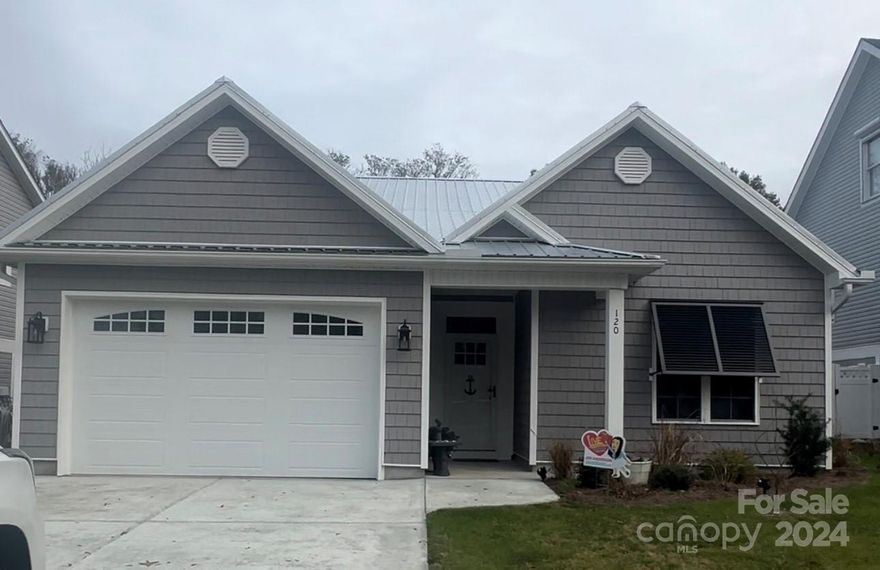 What's better than a new home?  How about a like new home with upgrades added! Less than a year lived in, extremely well maintained with many additions adding to the charm of this beach bungalow.  Black (functional!) bahama shutters, a wood privacy fence and landscaping in the backyard enhance the overall vibe - perfect for entertaining or just enjoying the peaceful west end of Oak Island.  On the spacious back screen porch, roll down sun shades have been added on all sides of the porch to help reduce heat and sun in the summer.  On the front elevation, the gray shake siding and metal roof with 2 car garage give this home great curb appeal!  Inside, LVP floors run throughout for easy maintenance (no carpet!) and don't miss the 9' ceilings with beautiful interior trim details throughout.  The kitchen features white shaker cabinets with contrasting dark hardware and plumbing plus stainless appliances.