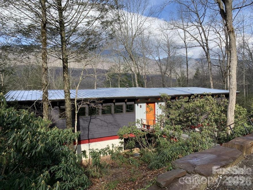 The Mitchell House, designed by architect Stephen Cluggish, blends contemporary design with nature, featuring steel beams allowing for extended cantilevers, soaring wood ceilings & structural beams,& expansive windows & 8’ high sliding glass doors that fill the home with light. Exquisite woodwork in white oak, cherry, & yellow pine, crafted by the owner, adds warmth & artistry. The open floor plan centers around a modern European wood-burning stove & a chef’s kitchen w/ hand crafted cabinets & an oversized honed black granite countertop. A thoughtful layout w/ spacious bedrooms on opposite sides of the house for enhanced privacy. Located in the gated River Run community, residents enjoy exclusive riverfront access on the South Toe, hiking trails, & proximity to the Blue Ridge Parkway & Mitchell Golf Course. Private wooded lot w/ stunning views of Mount Mitchell Range, the Mitchell House blends art, comfort, & functionality, offering endless inspiration for those seeking modern design.