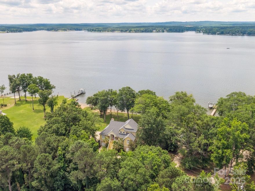 Breathtaking Custom Lakefront Estate on Main Channel! Every room boasts panoramic water views in this beautifully crafted home with rich hardwoods and quality millwork throughout the main level. With 4 bedrooms and 5 full baths, enjoy 2 bedrooms on main including a spacious owner’s suite with private balcony, plus an ensuite and another balcony-access bedroom upper level, plus loft—ALL with brand-new carpet. A gourmet kitchen offers counter seating and opens to a vaulted great room with fireplace and built-ins. Entertain with ease on the expansive covered porches, screened porch, and multiple decks. Outdoor luxuries include a hot tub, patio with fire pit, beach area, private boat ramp, boat lift, and two jet ski ports. The lower level features a rec room, flex room, full bath, and kitchenette—with elevator access to the main level. Ample storage, workshop, 2-car garage, washer/dryer, and new refrigerator convey. Lake living at it's finest on a rare Lake Wateree, light-filled retreat. Credit of $2500 at closing with preferred lender.