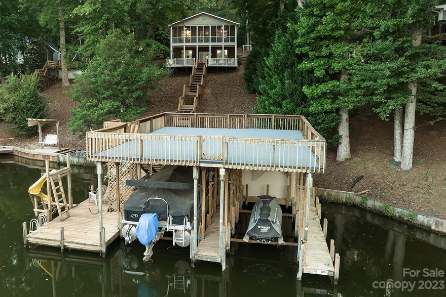 Fully furnished waterfront home nestled in the trees that provide glorious shade! Fantastically deep, deep water & large 2-Slip Boathouse w/ personal watercraft lift. Full open sundeck on top perfect for sunbathing. This quintessential floorplan features a beautiful open great room, kitchen w/ painted cabinetry & center island, dining area and a large screen porch looking over the lake! Primary bedroom & large full bath with garden tub and separate shower located on the main floor! Downstairs in the finished basement, you have two nice size bonus rooms to use any way you'd like and another full bath. The tall ceilings gives the basement a lovely open & airy feel! Nice den with lots of windows and glass doors that connects to a beautiful covered patio and two open octagonal decks that flank each side of the walkway leading directly to the waters edge. This is one of those pretty ones! Just a fantastic setting, with a glorious beautiful view of the lake. This one won’t last long!