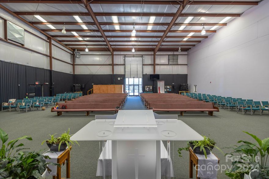 Located in a small industrial park .4 mi from Airport Rd off of Bradley Branch Road. Originally built out for a sports training facility with large weight room, batting cages, basketball court with poured rubber flooring, locker rooms, dining area. The facility is currently occupied by a church through 10/31/24. The building is 13,600 sf main level + 415 sf mezz for a total of 14,015 sf. DO NOT DISTURB TENANT! 
Highlights: Ceiling height: 26' clear; 
Handy location .4 mi from Airport Rd off of Bradley Branch Rd; 
Zoning: CI (Commercial Industrial) City of Asheville; Current tenancy expires 10/31/24
Dock installation study on file.