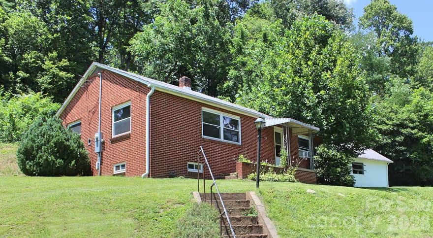 Welcome to this beautifully refreshed 2-bedroom, 1-bath home where small-town charm meets modern comfort, just minutes from the heart of Clyde. Nestled on a gently sloping 0.61-acre lot, this property offers a serene, picturesque setting with the convenience of nearby amenities—truly the best of both worlds.

Step inside and feel instantly at home in the bright, inviting interior, thoughtfully updated with fresh paint, new carpet, and stylish appliances. The functional layout creates an easy, natural flow from the cozy living area into a spacious kitchen, perfect for everyday living or gathering with friends and family. Each bedroom provides a comfortable retreat, designed for rest and relaxation.

Downstairs, a full basement opens the door to endless possibilities—whether you envision a workshop, home gym, recreation space, or future expansion. Outside, the detached garage with loft space adds even more flexibility for storage, hobbies, or creative use, while the classic brick exterior delivers timeless curb appeal that never goes out of style.

Located less than five minutes from downtown Clyde and just a short drive to Waynesville and Asheville, this home places you close to local shops, dining, schools, and healthcare—while still offering a peaceful place to unwind at the end of the day. With its thoughtful updates, versatile spaces, and inviting atmosphere, this property is ready to impress and easy to love.