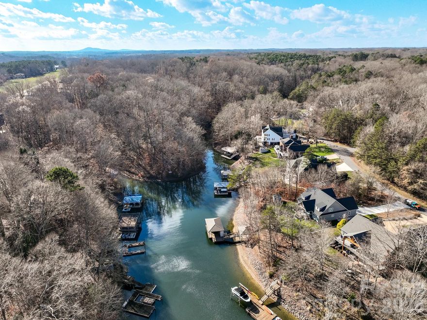 A rare opportunity awaits to own this gated 26-acre estate, seven springs on Lake Norman, complete with a private boat dock. The property showcases exceptional features, including a 2-acre spring-fed pond, a spacious 1,678 sq. ft. detached garage/workshop adaptable for multiple uses, former horse stalls, and a charming potting shed or she-shed. Ideally situated just outside the Long Island Airport strip, this remarkable estate offers endless possibilities and areas to explore. Additional amenities include state-of-the-art surround sound, a whole-home generator, an electric vehicle charging station in the garage, fruit trees, a full home theater in the basement with a 3D projector, and solid mahogany doors throughout. The outdoor living area is truly extraordinary, featuring a resort-style saltwater pool with waterfall and spa, a built-in grill, an outdoor fireplace, and a projector with screen. Multiple tiers of outdoor entertaining spaces create an unmatched setting for gatherings and relaxation. Inside, the great room is highlighted by an exquisite mirror imported from England, adding a sophisticated and timeless touch. The home boasts multiple fireplaces, rich Brazilian hardwood floors, dual grand staircases, and elegant marble flooring. The gourmet chef’s kitchen features double ovens, a gas cooktop, and sweeping views of the property from nearly every room. This exceptional estate is truly one-of-a-kind—an unparalleled offering that must be experienced in person to be fully appreciated.