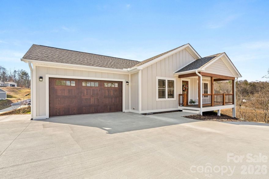 Looking for low maintenance and easy living? This one is it. Single level living in a new gated community in the Mars Hill area. Conveniently located a short distance from Main St, I-26 and an easy drive to Asheville or Tennessee, this home offers so much with easy living. A 1 story home on a crawl space, the main level garage provides easy access to the home. A small yard makes maintenance easy along with a smaller footprint for less upkeep. This two bedroom home lives large with the vaulted ceilings and open concept floorplan. There is a nice covered front porch and also a covered side deck - both finished with composite decking so there is no staining/painting required and upkeep is simple. This home features smart siding (not vinyl) and has great curb appeal. The concrete driveway give easy access to this cul-de-sac lot. There is a gas log fireplace in the living room with modern brick surround and custom mantel with shiplap accent wall above. You'll appreciate the kitchen island and breakfast bar, along with the granite tops, custom tiled backsplash & deep farmhouse style sink. A spacious laundry room is located adjacent and off the hallway. The Primary Bedroom has great natural light, ceiling fan, walk-in closet and an en-suite full bath with custom tiled walk-in shower and bench. There is a double vanity with great cabinet space. The second bedroom is also spacious and there is a 2nd full bath with tub/shower. Both bathrooms have matching granite tops. If you're seeking a move-in ready home of a finer quality and finishes in a gated community, then this one should be at the top of your list. See the property video here: https://listings.shindlersolutions.com/video/IexvS011eII1ZxXeTCAr7MLu9CNP3jIQIncKTh7nmndc