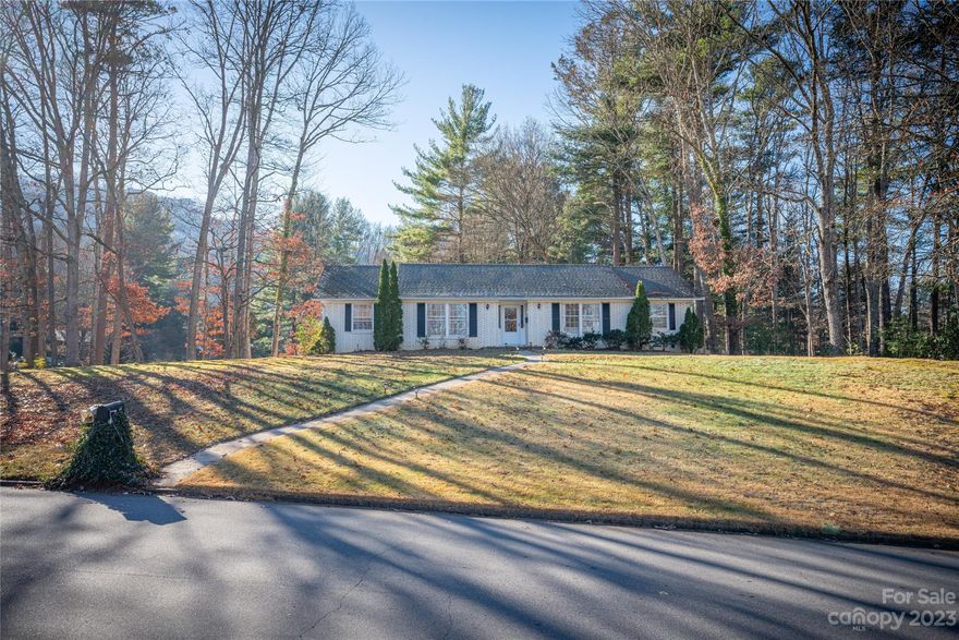 Expansive brick ranch with lower level on gentle 0.68 acre corner lot in beautiful North Asheville Woodland Hills location.  Just minutes to downtown Weaverville or downtown Asheville. Incredible light-filled open floor plan with large rooms and ample living space! Mid-century style upgrades including interior wood railings, ceiling beams, new kitchen with white quartz countertops, grey/blue cabinets, graphic backsplash, Smart Samsung black stainless appliances, hood vent, pot filler and new LVP flooring. MULTIPLE LIVING OPTIONS with 3 BRs, 2 baths, ON MAIN LEVEL along with living, dining, den with fireplace and kitchen. Finished lower level en suite with additional living area and fireplace and its own entrance is perfect as an in-law suite with minor modifications. Large two car garage with extra storage, on large corner lot with deck and fenced in sunny backyard. Refrigerator, washer and dryer convey. This is a gem of a find in a coveted established neighborhood at a great price!