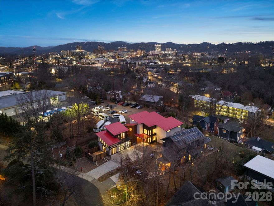 Modern architecture meets effortless indoor/outdoor living in this WECAN/River Arts District stunner! Panoramic Blue Ridge mountain views and sparkling downtown lights frame a sun-filled interior anchored by a floating steel staircase and soaring ceilings. An 18’ LaCantina door opens the living area to a private outdoor haven with heated pool, hot tub, bluestone patio, custom fireplace, and low-maintenance Global Syn-Turf yard. Upstairs, the primary suite offers an expansive walk-in shower, with two additional bedrooms plus a third floor suite featuring built-ins and a trundle bed. Additional spaces include a gym and art studio/flex space with a peaceful  side courtyard. A separate guest suite/office with full bath provides added privacy (or potential to rent). A rare blend of modern design, thoughtful spaces, and a premier location just steps away from Downtown Asheville & RAD–this home is not to be missed!