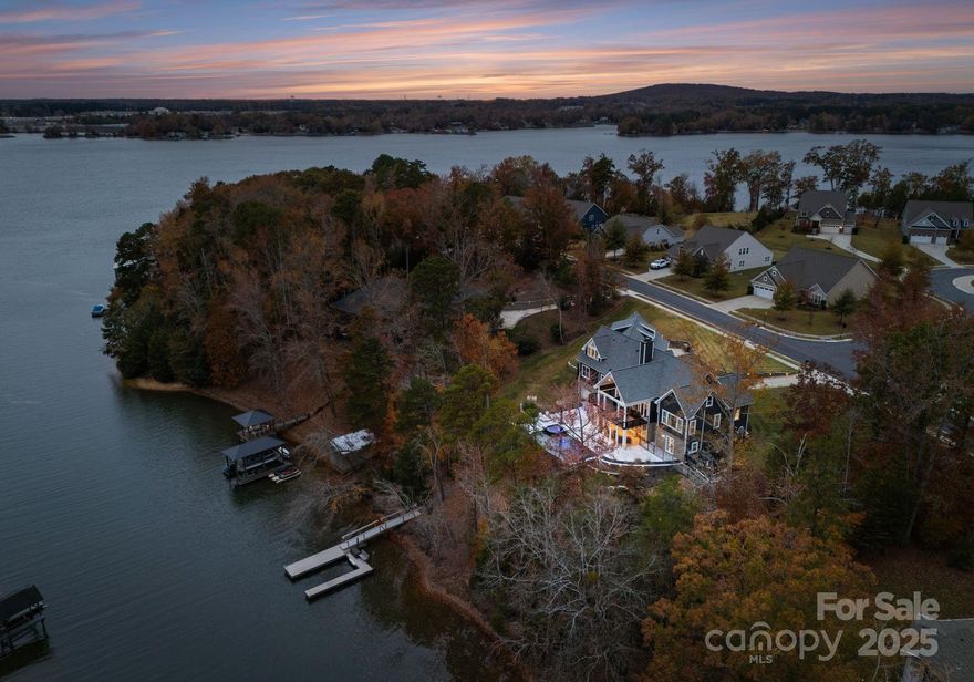 Absolutely stunning waterfront retreat on Lake Wylie! Situated on just over an acre within the desireable Palisades area with no HOA restrictions, this exceptional 6 bedroom, 5 full/2 half bath property offers unmatched freedom and luxury in one of Charlotte's most coveted locations. A charming rocking chair front porch welcomes you into a breathtaking 2-story great room, highlighted by a dramatic three sided floor-to-ceiling stone fireplace. The open dining area flows seamlessly into the chef's kitchen, featuring an oversized island with breakfast bar, 36" gas cooktop, double wall ovens and a full size side by side refrigerator and freezer. Just off the great room, the covered deck provides one of many inviting outdoor living spaces with tranquil lake views. The main level primary suite impresses with a spacious 17x21 bedroom overlooking the water, along with spa-inspired bath and walk-in closet. Two additional bedrooms, a jack and jill bath, walk-in pantry and a large laundry room leading to the 3-car garage complete the main level. Upstairs, you'll find a full private apartment  -- ideal for in-laws, guests, and more -- offering a beautiful kitchen, open living area with lake views, a generous bedroom, 1.5 baths, pantry and laundry. The expansive basement adds even more versatility featuring a living room/rec room, full kitchen, 2 bedrooms and 2 full baths. Over 1,000 sf of unfinished space offers endless possibilities for storage, home gym or future expansion. A separate one-car garage with workshop is perfect for a golf cart, tools and lake toys. Walk out from the basement to a spacious screened porch overlooking the inground pool, hot tub, grill station, built-in firepit and, of course, Lake Wylie. Follow the gentle path down to your private dock and enjoy boating, water sports, fishing or peaceful sunset views. This unique property offers true lake living with unmatched convenience. Schedule your appointment to see this incredible property today!