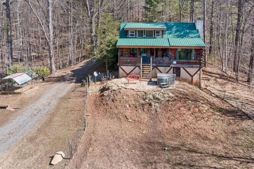 Looking for a REAL log cabin with views and privacy? This is it! Adorable open concept living/dining/kitchen. Vaulted ceilings, lots of windows, and VIEWS. "Authentic" in every way! 2 cute bedrooms with flex space in the loft. Remodeled kitchen, newer electrical/plumbing, wood stove, etc. You'll love the way this one flows. Good vibes! 6.50 rolling acres w/ fenced pasture, barn for your furry friends, woods, trails, and a creek. The cherry on top is a hot tub on the stone patio to soak it all in and leave the hustle and bustle behind. Front & back porch, new 3+ car carport (top notch!), AND a separate 2 BR septic has been added for RV/guest house/2nd homesite. No known short-term rental restrictions so...mini-farm, vacation getaway, short-term rental goldmine? Reliable high-speed internet (Telemetrix), easy and GORGEOUS drive in through the Upper Crabtree area, and paved almost all the way up. A great value with so many different uses AND it's priced right. Check out the drone footage!