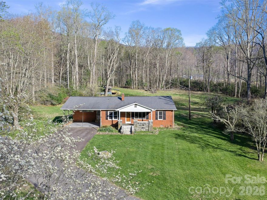 Situated on over 3 private acres, this charming 1937 brick Craftsman-style home offers the perfect blend of timeless character and modern updates. The property features a beautiful expansive yard, level for easy mowing in both front and back, complemented by peaceful wooded acreage that provides exceptional privacy and a serene setting. Conveniently accessed from a state-maintained public road, the home welcomes you with a paved
driveway and carport for easy everyday living. A spacious covered front porch showcases stunning original stonework—an ideal spot to relax and take in the surroundings. Inside, the home has been thoughtfully renovated with a fresh, updated kitchen and bathrooms featuring new appliances, countertops, ceiling fans, and stylish light fixtures. Original wood floors add warmth and character throughout, while a newer heat pump and propane furnace ensure year-round comfort. The layout offers a generous kitchen and dining area, three
comfortable bedrooms, and two spacious bathrooms. Additional features include a sunroom, back patio for outdoor enjoyment, and a separate laundry and storage room for added convenience. Centrally located between Bakersville and Spruce Pine, this move-in ready home is affordably priced and offers a rare opportunity to enjoy classic craftsmanship with modern ease in a peaceful mountain setting. There is a shared spring with a spring box and pump. Shared with 58 Possum Trot and the small house on the corner. The spring once served 4 houses and is a very reliable water source. According to the family, it has been in use for over 100 years. The pump is attached to the electric service of 58 Possum Trot. A shared spring agreement will be drafted at closing to reflect all expenses for future repairs of the spring and pump will be equally shared and a monthly or yearly agreed upon amount for the electric use of the pump.