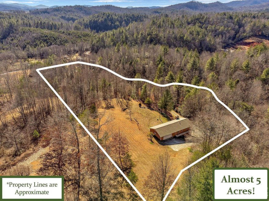 Once you pass the gated entry, up the long gravel driveway sits this well kept brick ranch situated on almost 5 acres of seclusion complete with a large creek running adjacent to the driveway, wrap around porch and all the privacy you will need. The interior features many updates included updated kitchen and bathrooms, original hardwood floors, stainless steel appliances, 2 bedrooms, 2 bathrooms, an office, open floor plan, dedicated laundry space and more. The primary bedroom has an attached bath and 2 large walk in closets. Sit on your private wrap around deck an take in the breathtaking mountain views over looking the well kept grounds and large running creek. Unfinished basement features 16 foot ceilings, large workshop and all the space you will need for storage or any hobby you may dream of. The 2 car attached garage located just off the kitchen makes the perfect entry into the home. Located within walking distance to Lewis fork river and short drive to the Blue Ridge Parkway.