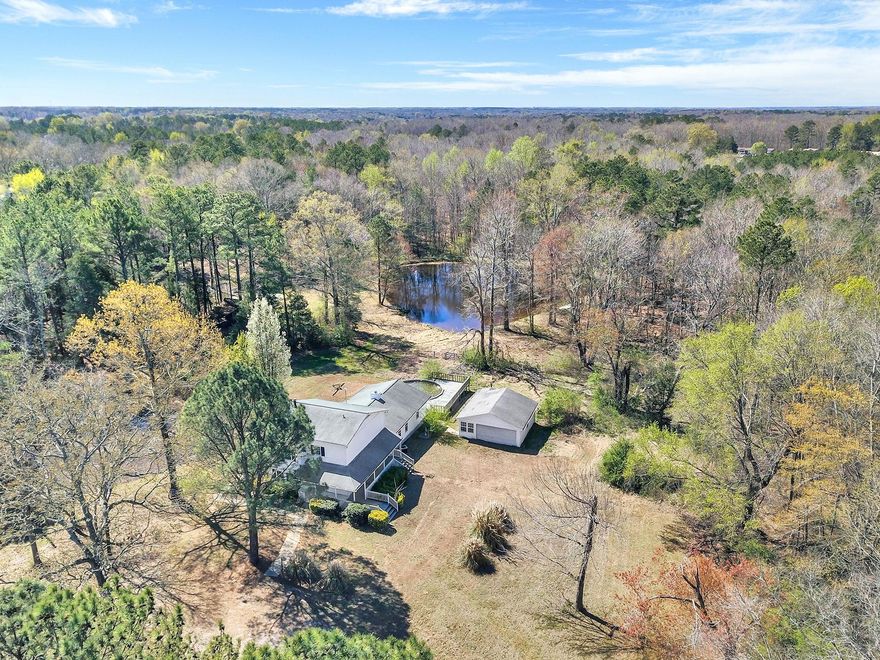 Welcome to your homestead in a quiet country setting w/ a large pond. Very spacious home with 4 bedrooms, 2 full bathrooms, & a laundry room. Character filled w/ stone accent walls, a bay window, & a wood burning stove in the den with a separate dining/office area. Step down to a great room alongside a rec room & the main level bedroom. Head out of the back or side door to a large decking system leading you to an above-ground pool. Sit on the back deck & enjoy the tranquility of country living while you watch the wildlife around you including deer & mallard ducks swimming in the peaceful pond which is stocked with bass, crappy, brim, and gar for great fishing. Detached garage w/ a wood burning stove is perfect for your workshop or to store your toys. This 5.6 ac parcel is mostly fenced in & is adjacent to another 3.57 ac lot being sold by the same seller. Lots of space with tons of potential for you to come in, give it some TLC, & make it your own. Property is being sold as-is.