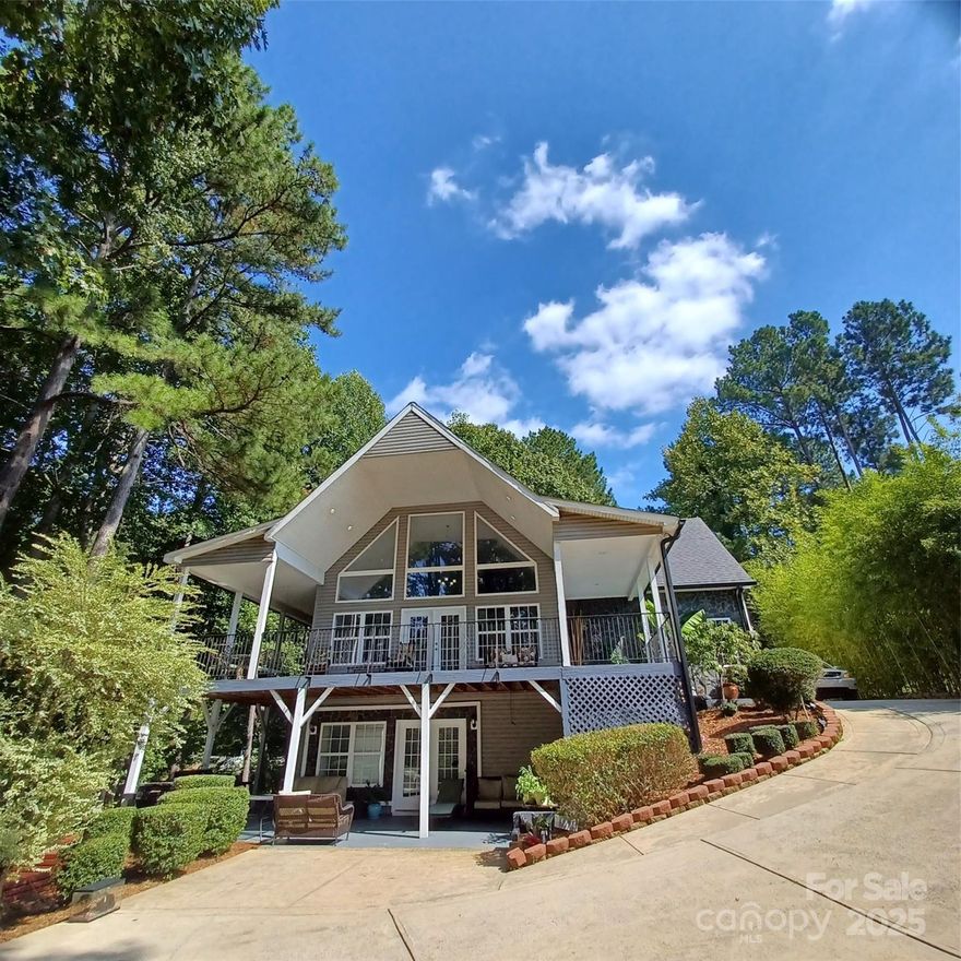 Great price improvement! This custom-built waterfront home on Lake Norman features four bedrooms and five bathrooms. The tri-level design offers primary living spaces on the main floor, with additional quarters in the walk-out basement. Loft with water views, a bonus room, and a separate office, all equipped with closets. The expansive L-shaped wrap-around covered patio and balconies provide an ideal setting to enjoy the lakeside breeze. Large, wooded lot, adorned with mature trees, ensures ample shade and privacy. Conveniently located adjacent to the community boat ramp and slips, the property is also near Sherrills Ford's shopping and dining areas. The main floor includes a spacious primary bedroom suite, while the basement level an in-law suite with a private, complete with kitchen, dining space, laundry, and two bathrooms. Additional highlights include elegant hardwood floors, tile accents, extra parking for a personal boat, and a lockable gate for enhanced security and privacy.
