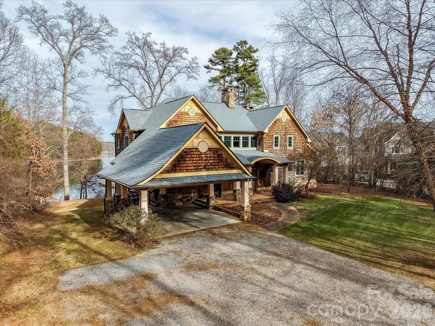 Amazing, Waterfront Home with exceptional craftsmanship and timeless character throughout! With a generously sized, asthetically pleasing, 2 car carport & huge, travertine front porch with custom front door & windows, you will want to see all this home has to offer! Inside, the 2 story great room centers huge windows for incredible lake views & a massive, stone fireplace with propane capability, offering the option to burn either propane or wood. An additional outdoor fireplace on the wrap around, lake facing, covered deck features a capped gas line, ideal for future gas logs, though it has traditionally been enjoyed as a wood-burning fireplace.

The kitchen and upstairs mini-kitchenette (conveniently located just outside the hallway bathroom) are both finished with elegant granite countertops. The main Chef's Kitchen offers high end, stainless steel appliances, large center island, custom cabinetry, lighting & a cozy breakfast nook with beautiful views! The dining room showcases custom-built cherry wood shelving with a lower cabinet and a warm wood countertop, complimented by a matching custom cherry wood dry bar that seamlessly connects the dining and living areas. Flanking the living room fireplace on both sides are additional custom cherry wood built-ins, adding both beauty and functionality. 2 Bedrooms (both include walk in closets) are conveniently located on the main level with an easily accessed full bath!

Throughout the home, you’ll find over 30 custom, hand-crafted cherry wood interior doors, built by renowned builder Pete Zagaroly, a rare and striking detail that elevates the home’s quality. The flooring is equally impressive, featuring reclaimed heartwood pine sourced from the historic Cannon Mills factory, offering rich character and durability.

The Owner's Retreat is located on the upper level & features a private door to the spacious balcony to enjoy exclusive sunset, water views! The primary bathroom includes a tile surround garden tub & luxurious steam shower for spa-like relaxation. The upper level landing makes a statement with a spacious loft area & flex space (with plenty of windows for perfect lake views) that can be utilized as an office.

This one-of-a-kind property located on a half acre with fabulous water & ultimate privacy with mature trees/landscaping blends historic materials, custom millwork, and thoughtful design—truly a home that must be experienced to be fully appreciated.