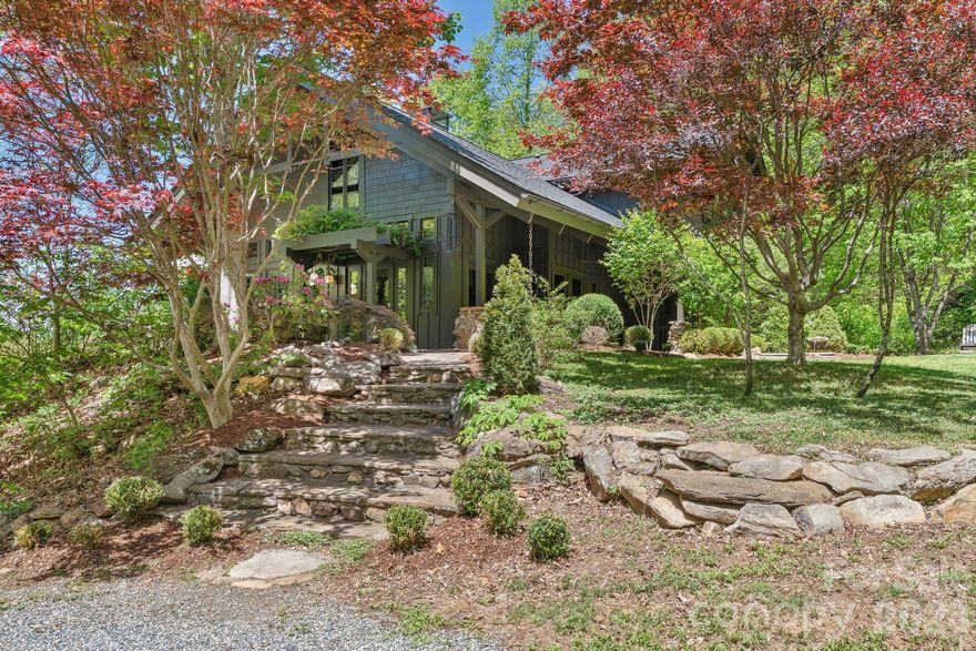 Nestled on more than 19 expansive acres at an elevation of 3,000 feet, this Barnardsville sanctuary offers the ultimate private mountain retreat in the heart of Big Ivy, just 20 minutes from Weaverville and 30 minutes from Asheville. Beautifully updated Arts and Crafts-inspired home features a grand open-concept living room with a soaring post-and-beam cathedral ceiling, loads of windows, and a stunning stone fireplace. The remodeled kitchen features quartz countertops, a subway tile backsplash, and a central cooktop island that flows seamlessly into a cozy dining area. Retreat to the luxurious second-floor primary suite, complete with vaulted ceilings, a private screened-in porch, and a spa-like bathroom featuring a freestanding soaking tub, double vanities, and a tiled step-in shower.  Mountain views and nature encircle this special property— offering incredible outdoor living. Multiple stone patios offer gathering and dining areas along with a built-in firepit. The spring-fed pond with a private dock is the perfect spot for daytime fun, while the private hot tub and outdoor shower is ideal for bathing under the starry night sky. Adding to the property’s immense charm is a separate rustic cabin studio—perfect for an artist’s getaway or home office—equipped with a wood stove and a large deck overlooking the pond. With modern conveniences like a whole-house generator, radiant-heated floors, a tankless water heater, and wooded trails at your doorstep, this end-of-the-road estate is a rare jewel of mountain living.
