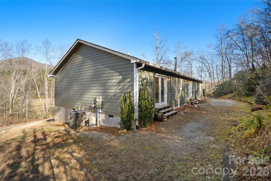 This site-built ranch home offers peace and privacy on 1.9 acres in Buncombe County, with the convenience of one-level living and seasonal mountain views. The updated layout features an open floor plan, spacious rooms and walk-in closets. The property includes an unrestricted deed, open-use zoning and no HOA. Inside, the great room and kitchen feature solid white oak floors, complemented by a distinctive 1920s wood cook stove. Recent updates include fresh interior paint, new carpet in two bedrooms, and new luxury vinyl flooring in the baths and third bedroom. The home is privately set, yet just approximately 15 minutes from downtown Asheville and five minutes from shopping and dining. Nearby Cane Creek offers trout-stocked waters for fly fishing. Sheetrock not permitted in 433 square feet of the home. Agent is seller. The green grass was added in photo 32 because a third septic line was installed, and the yard had to be reseeded and straw added. The woodstove heats the entire house, makes wonderful food and can be removed upon request.