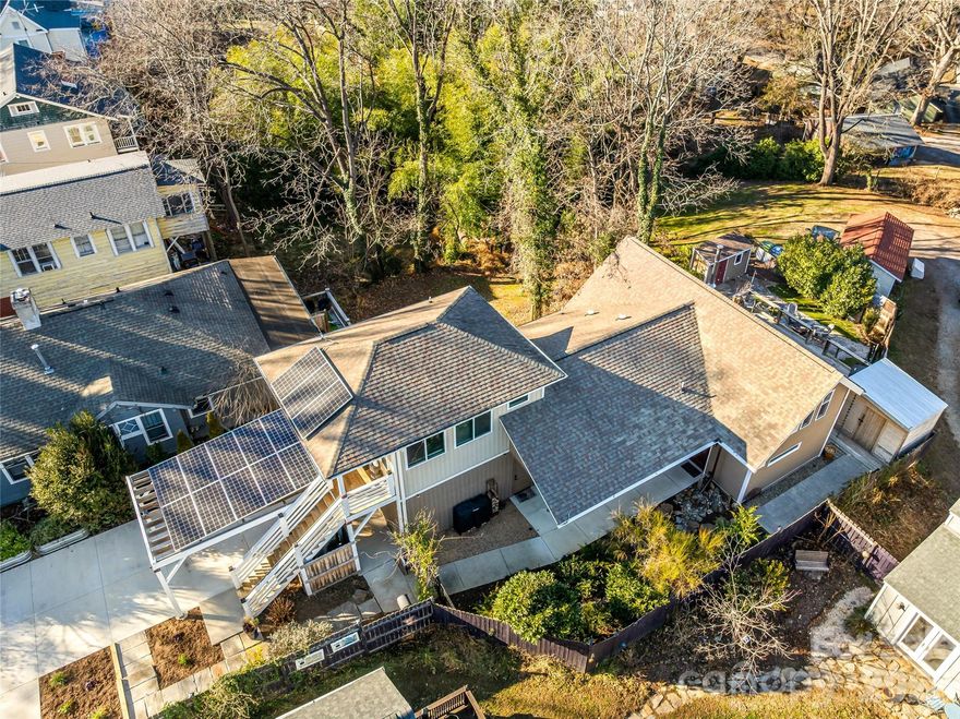 Discover modern mountain living in the heart of Asheville’s coveted Northside neighborhood, just minutes from downtown’s best shops, restaurants, and nightlife. This newer-built home stands out with high-end finishes, abundant natural light, and flexible living spaces. The entryway opens into a spacious great room, where vaulted ceilings and a cozy wood-burning stove create an inviting atmosphere. Custom built-in cabinetry and a striking waterfall island anchor an open concept kitchen-great room, creating a polished, functional space ideal for both everyday living and entertaining.

Just up the stairs, a loft offers a versatile space for a guest area, reading nook, or home office, with views of the Grove Park Inn, adding to its charm. The primary suite is privately tucked away at the rear of the home and includes a generously sized en-suite bath, creating a peaceful retreat.

Head outside to the back deck to take in mountain views and the detached tiki bar/party shed is equipped with electricity and offers flexible use—ideal for an outdoor bar setup, game-day hangout with an outdoor TV, or additional storage as needed.

A studio apartment with a separate entrance is located on the second level, making it well-suited for short-term rental income or house hacking. Buyers seeking energy efficiency will appreciate the Sugar Hollow solar system. Abundant off-street parking includes a carport and a one-car garage, with plans to expand the garage available upon request.

Centrally located, full of character, and designed for modern Asheville living—this home truly offers it all.