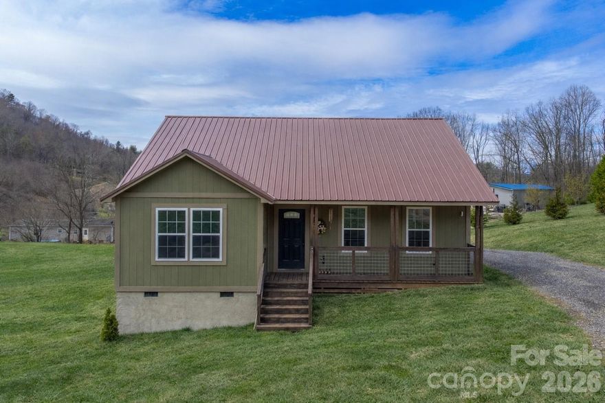 A peaceful country setting surrounds this two year old home, featuring an open floor plan and thoughtfully designed living spaces. The kitchen offers a gas range, oversized pantry, and ample workspace, making it both functional and inviting. The home includes two bedrooms, including a primary suite with a private bath, as well as a secondary bedroom for guests or additional use. LVP flooring runs throughout the home, complemented by a durable metal roof and an electric fireplace that adds warmth to the living area. Low-maintenance construction combined with tasteful finishes provides both comfort and lasting appeal. Located conveniently between Waynesville and Asheville, this gorgeous property offers an escape from the world, while being just minutes to local amenities.
