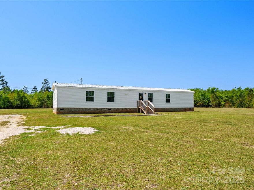Enjoy peaceful country living on 3.2 flat, open acres in Kershaw! This well-kept 3-bedroom, 2-bath manufactured home offers 1,140 sq ft of comfortable living space. Step inside to a bright living room on the right and a spacious kitchen to the left, complete with a center island, stainless steel appliances, and a farmhouse sink perfectly positioned under a wall of windows overlooking the backyard. Whether you're looking for a little land to stretch out or room to grow, this property offers the space and setting you’ve been searching for!