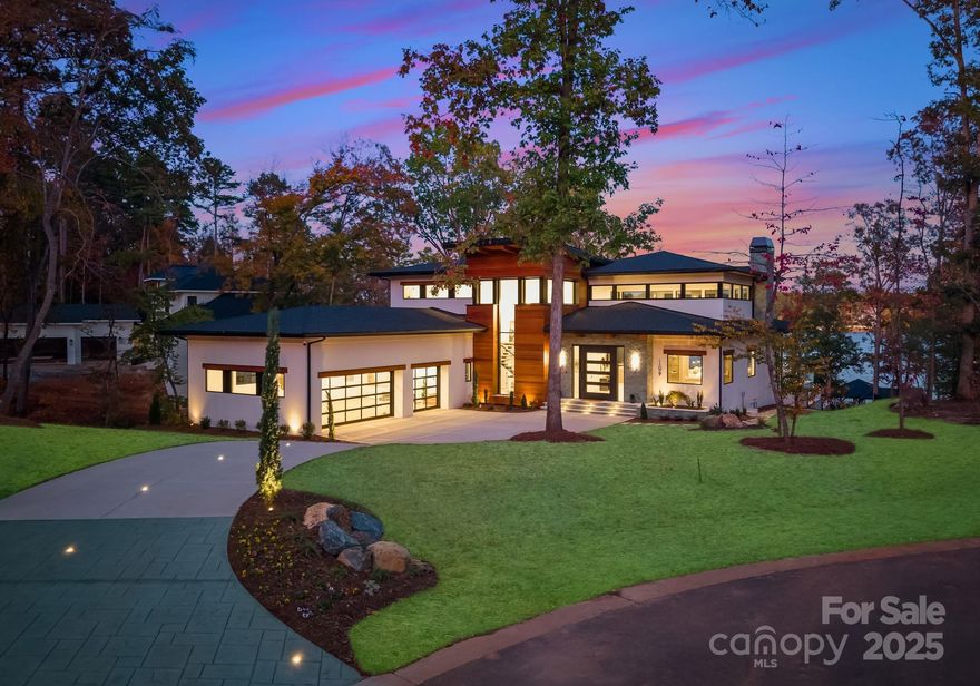 Exquisite Waterfront Masterpiece on Lake Tillery – Discover an architectural work of art on the shores of Lake Tillery. Designed and built by Artistic Contractors, one of Charlotte’s premier design/build firms, this 7,940 sq ft modern lakefront retreat embodies warmth, innovation, and serenity. Set on nearly an acre of gently sloping land beneath mature trees, this property blends natural materials with bold geometry to create one of the most extraordinary residences in the Carolinas.
Homes in the sought-after Edgewater community have consistently sold above $600 per sq ft since 2022, with a neighboring property closing in August 2025 at $672 per sq ft. Priced at only ~$660 per sq ft, this fully loaded lakefront showpiece offers unmatched design and luxury—an exceptional value for a home of this caliber.
Step through the monumental 10’ x 10’ pivot door and into the breathtaking 1,400 sq ft atrium great room—a soaring, light-filled space combining living, kitchen, and dining under a 28-foot pyramidal clerestory ceiling clad in rich imported Peruvian Cumaru wood. Supported by striking exposed steel beams, the atrium provides a grand opening through a 24-foot folding glass wall to covered terraces. This room stands among the largest and most architecturally striking private spaces in the Carolinas.
Throughout the 6-bedroom, 5.2-bath residence, form and function meet effortlessly. The chef’s kitchen features a 10’ x 6’ waterfall island, professional Monogram appliances, Miele induction cooktop, and concealed scullery. The great room’s Dimplex 74” linear fireplace anchors a dramatic wall of book-matched soft stone and carved wood panels. The floating mono-stringer staircase with glass railing and 3” white oak treads rises like a sculpture.
The primary suite is a sanctuary of peace with floor-to-ceiling glass windows offering panoramic lake views. The spa-inspired bath features a freestanding tub, 24” rain shower over a Cumaru deck floor, and spacious his-and-hers closets with custom cabinetry and ambient LED lighting.
Outdoor living exceeds expectation: over 1,700 sq ft of covered decks and terraces finished with Cumaru ceilings and imported Indonesian white Palimanan Limestone floors.  Glass railings, ceiling fans, built-in speakers, and motorized screens differentiate the outdoor living from any competition. A resort-style saltwater infinity pool and spa clad in Indonesian Sukabumi stone glows in deep lagoon hues, surrounded by matching stone planters and Palimanan limestone decking. The outdoor kitchen includes a Coyote 42” grill, Cumaru hood, sink, and cabinetry for effortless entertaining.
The property’s private 1,200 sq ft dock offers two covered boat slips and a covered entertainment area overlooking the long-range views of Lake Tillery.
Additional features include all-aluminum thermally broken windows and doors with Low-E argon-filled glass, open-cell foam insulation, tankless hot water, smart surveillance and lighting systems, 200+ LED recessed can lights, and an EV-ready three-car garage. An underground irrigation system pumps directly from the lake to keep the landscape lush year-round.
Every element—wood, steel, stone, and glass—was selected for beauty, durability, and emotional resonance. This is not just a house; it’s a sanctuary designed to inspire joy, peace, and creativity. Experience the art of living at 109 Tidewater Court—an extraordinary waterfront retreat where design and nature meet.