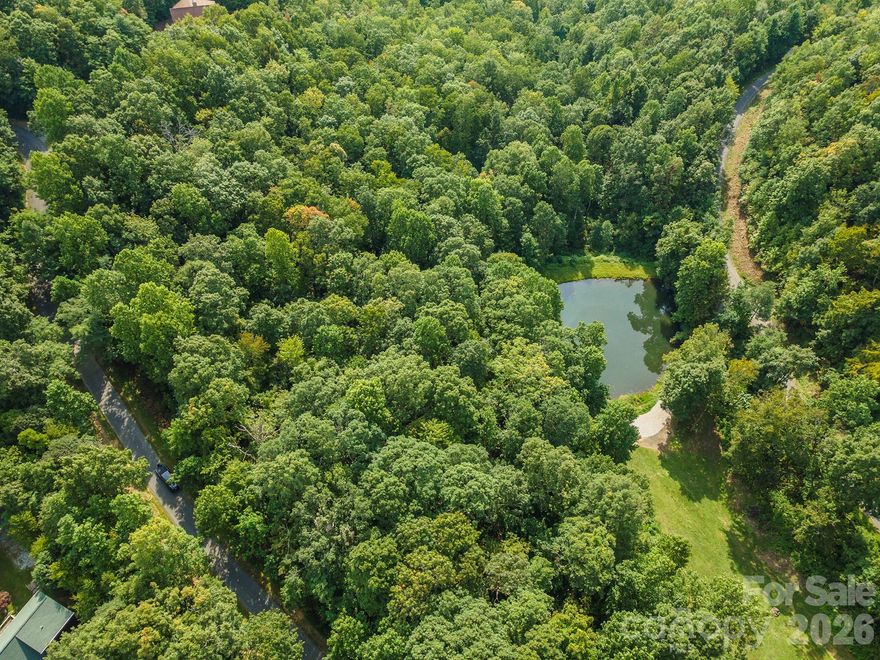 Have you seen this lot yet? If not, you’re missing out. Septic and well permits in place. Ready to start your home building project. Tucked within the quiet forest of Gateway Mountain, this 1.84-acre parcel with a spectacular pond and Mountain Views is a story book setting. Sheltered by tall hardwoods and draped in mountain laurel, rhododendron, and fern, this homesite offers a rare combination of privacy, easy build potential, and stunning pond frontage. The gentle slope provides flexibility for building, whether your dream is a cozy timber cabin or a modern mountain escape with glass walls opening to the view. There’s space to breathe, garden, and grow — all surrounded by the natural rhythms of the Western North Carolina mountains. Located in the gated community of Gateway Mountain, residents enjoy miles of walking trails, private lakes, creeks, and picnic areas, all lovingly maintained to preserve the land’s wild beauty. This is not a crowded subdivision — it’s a true nature sanctuary, where each property is spacious, wooded, and alive with mountain character. And though you’ll feel far away from everything, the essentials are close at hand. The vibrant small town of Old Fort is just down the mountain, and Asheville, Black Mountain, and Marion are an easy drive away — offering art, music, local markets, and restaurants that celebrate mountain living. Here, you can disappear into the woods without disconnecting from the world entirely. HOA fees cover road maintenance, the security gate, and the preservation of this extraordinary mountain environment. Don’t wait long, someone is going to fall in love with this place — it might as well be you.
