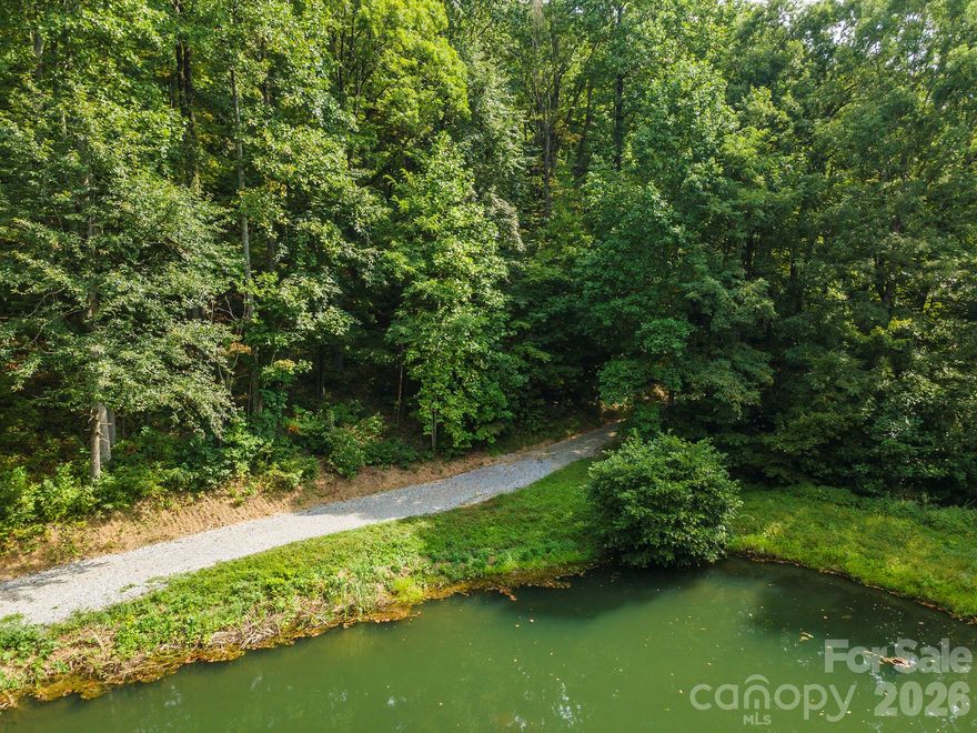 Have you seen this lot yet? If not, you’re missing out. Septic and well permits in place. Ready to start your home building project. Tucked within the quiet forest of Gateway Mountain, this 1.84-acre parcel with a spectacular pond and Mountain Views is a story book setting. Sheltered by tall hardwoods and draped in mountain laurel, rhododendron, and fern, this homesite offers a rare combination of privacy, easy build potential, and stunning pond frontage. The gentle slope provides flexibility for building, whether your dream is a cozy timber cabin or a modern mountain escape with glass walls opening to the view. There’s space to breathe, garden, and grow — all surrounded by the natural rhythms of the Western North Carolina mountains. Located in the gated community of Gateway Mountain, residents enjoy miles of walking trails, private lakes, creeks, and picnic areas, all lovingly maintained to preserve the land’s wild beauty. This is not a crowded subdivision — it’s a true nature sanctuary, where each property is spacious, wooded, and alive with mountain character. And though you’ll feel far away from everything, the essentials are close at hand. The vibrant small town of Old Fort is just down the mountain, and Asheville, Black Mountain, and Marion are an easy drive away — offering art, music, local markets, and restaurants that celebrate mountain living. Here, you can disappear into the woods without disconnecting from the world entirely. HOA fees cover road maintenance, the security gate, and the preservation of this extraordinary mountain environment. Don’t wait long, someone is going to fall in love with this place — it might as well be you.