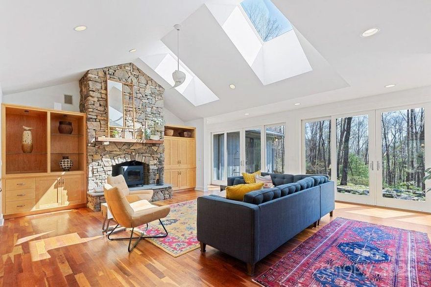 Nestled on 20 tranquil acres just 12 minutes from downtown Asheville, this private mountain estate seamlessly blends timeless design with natural beauty. The single-level residence welcomes you with cherry wood floors, stone fireplaces in both the living room and owner’s suite, and two sun-filled bedroom ensuites. A separate guest wing, featuring a private bath, deck, and outdoor shower, offers guests a boutique retreat experience. Trails lined with native wildflowers lead to a meditation labyrinth and a landmark historic stone chimney and patio that celebrate the land’s history. The detached studio is perfect for an artist’s atelier, yoga space, or private office. Every corner is meticulously landscaped with waterfalls and curated flora, providing seclusion while keeping Asheville within reach. Plus, the residence utilizes solar energy, reducing both environmental impact and utility costs, and ensuring year-round comfort for its owners.